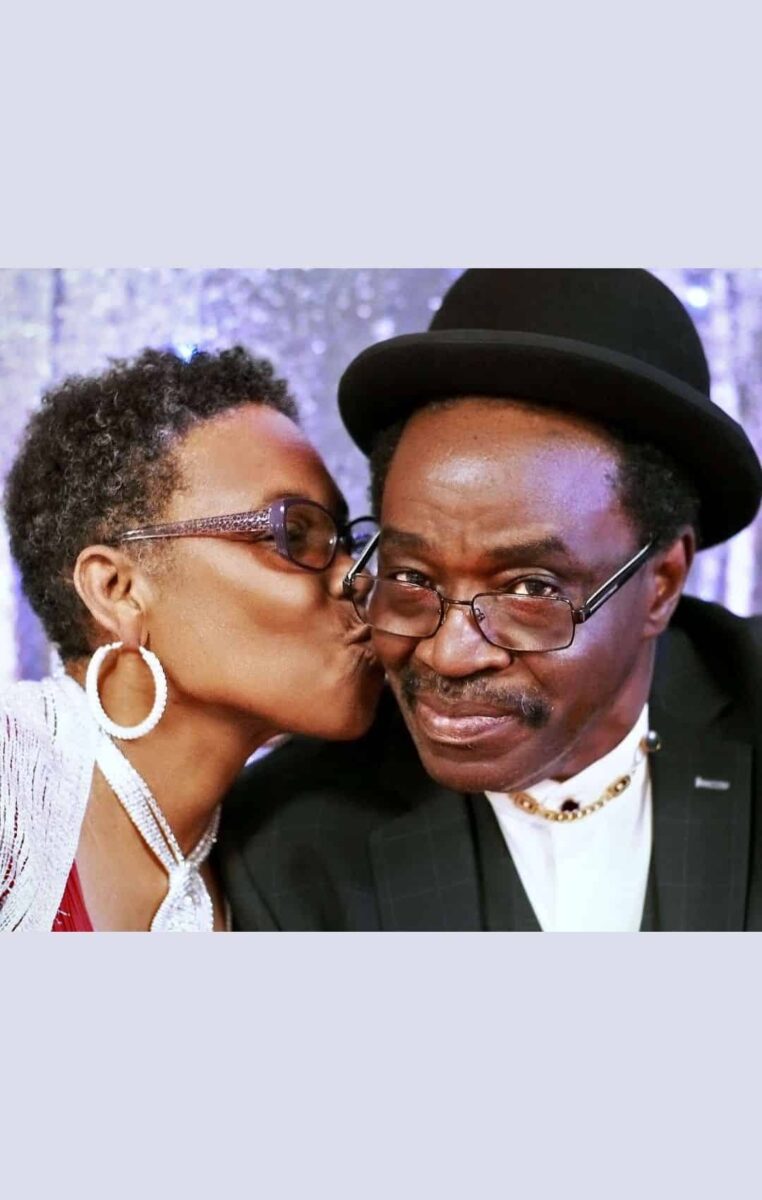 A Man With Glasses And A Woman Kissing Each Other.