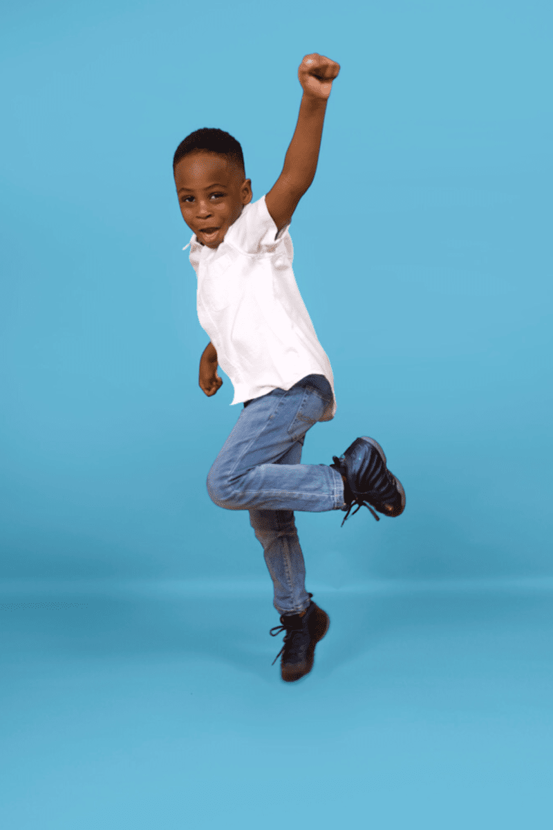A Young Boy Jumping On A Blue Background.
