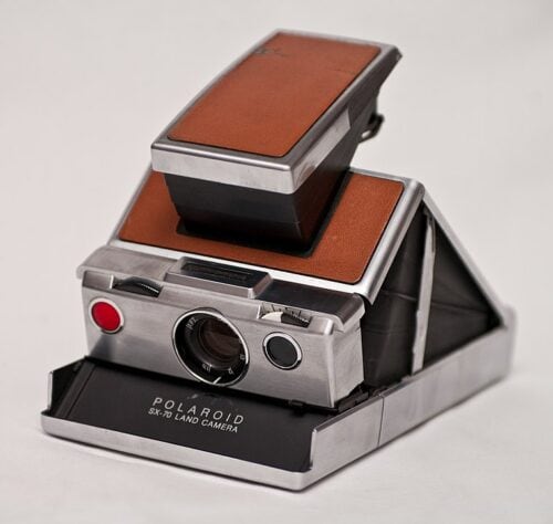 A Vintage Polaroid Camera With A Stylish Brown Leather Cover, Showcasing The History Of Photography.