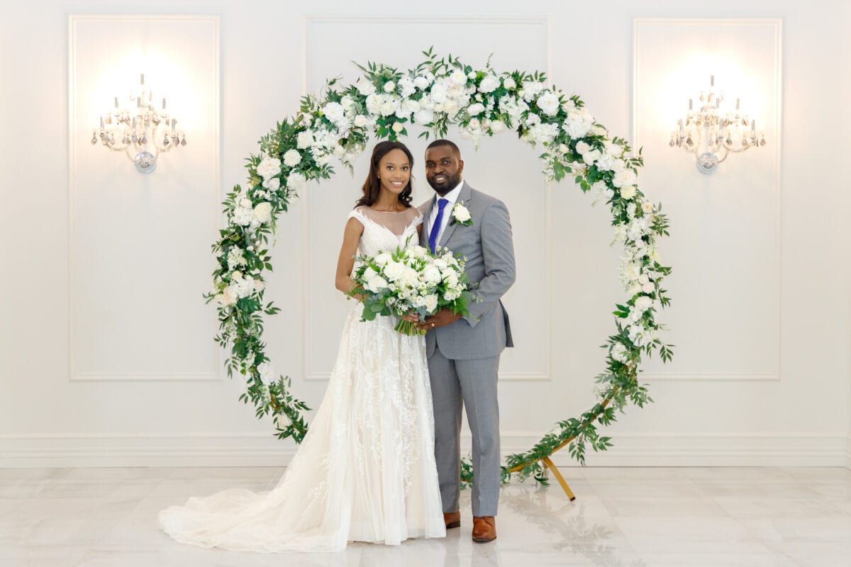 Wedding Photography Of A Bride And Groom In Front Of A Floral Wreath.