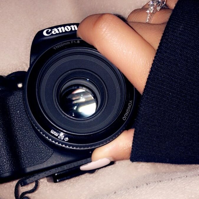 A Woman'S Hand Holding A Canon Dslr Camera For Photography Beginners.