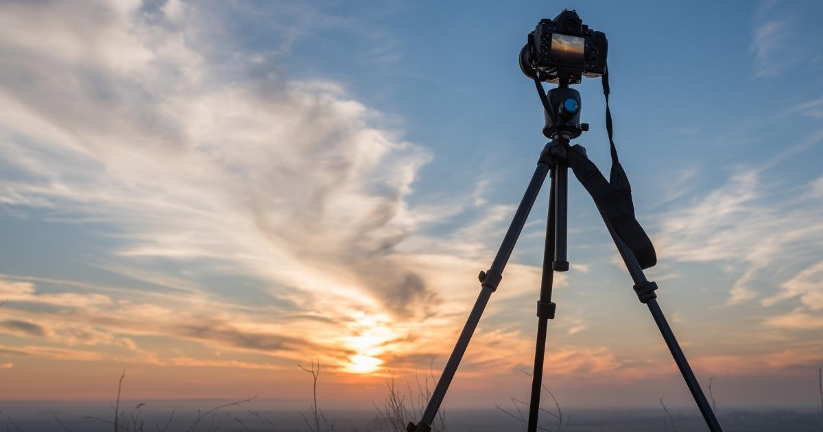 A Tripod With A Camera Capturing A Sunset.