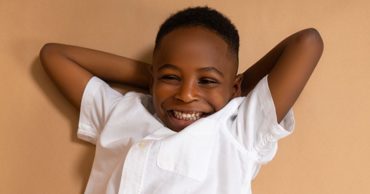 A Young Black Boy Poses On A Beige Background.