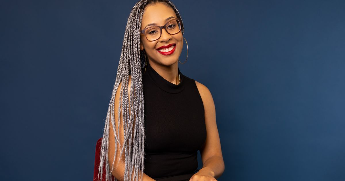 A Woman With Glasses And Braids Posing For Pictures.