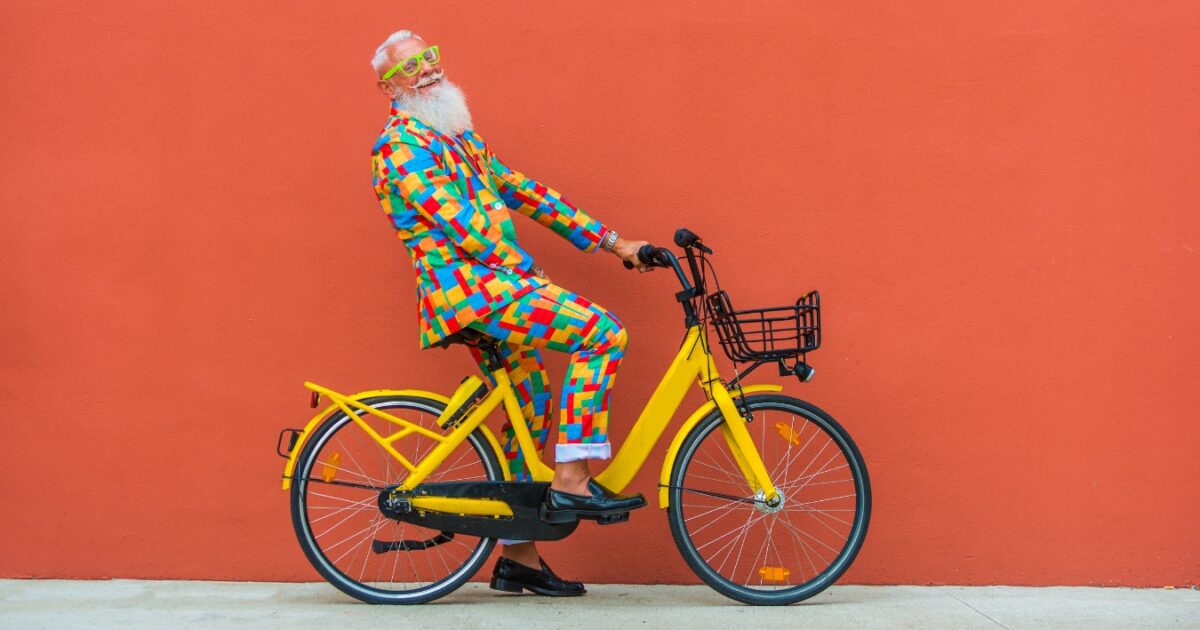 A Man Dressed In A Colorful Outfit Riding A Bicycle In A Photoshoot.
