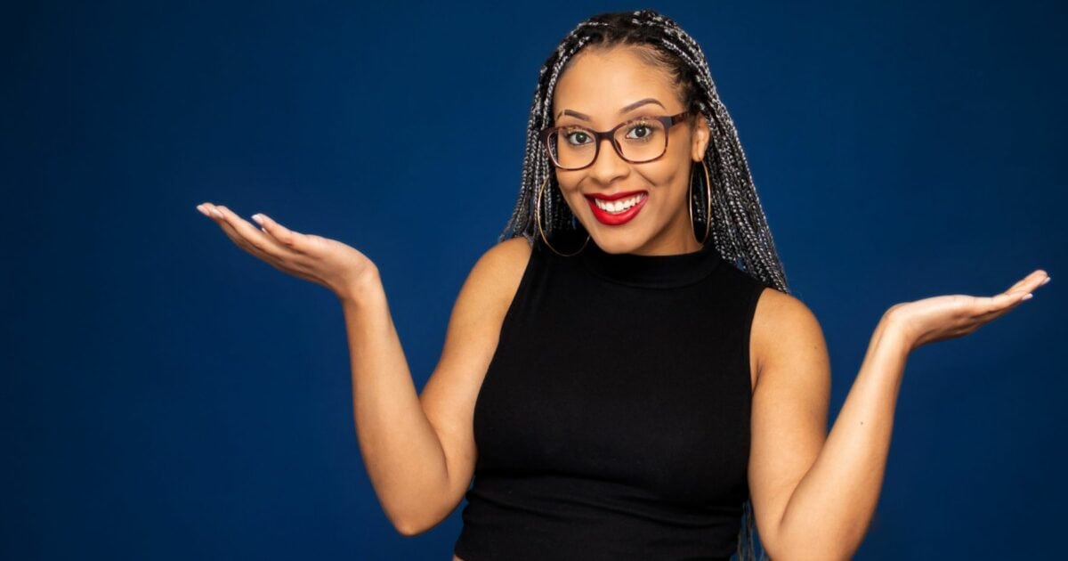 A Black Woman With Glasses Is Striking Photography Poses In Front Of A Blue Background.