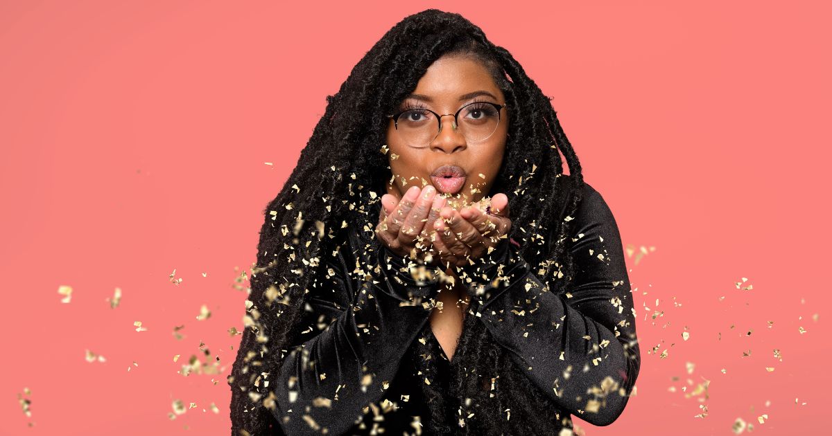 A Woman With Dreadlocks Striking Poses And Blowing Out Gold Confetti.