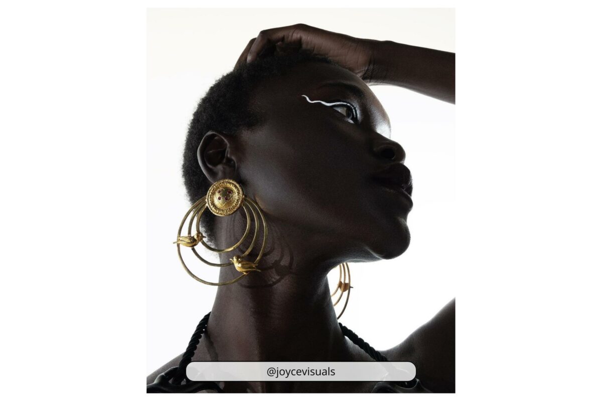 A Black Woman Wearing Gold Hoop Earrings Poses For A Photography Art Session.