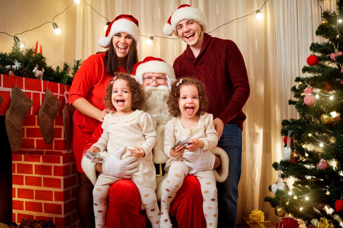 Santa Claus And Family Posing In Front Of A Christmas Tree During A Photoshoot.