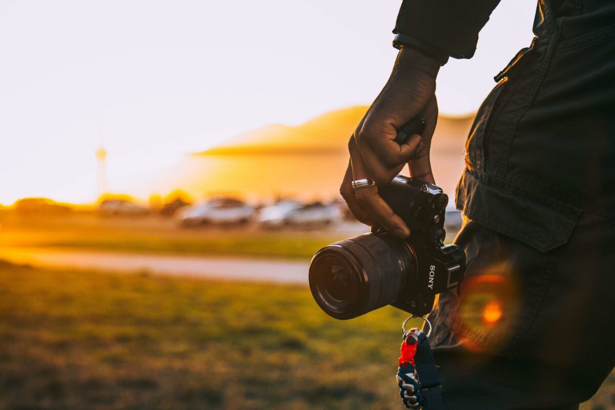 A Person Holding A Camera At Sunset.