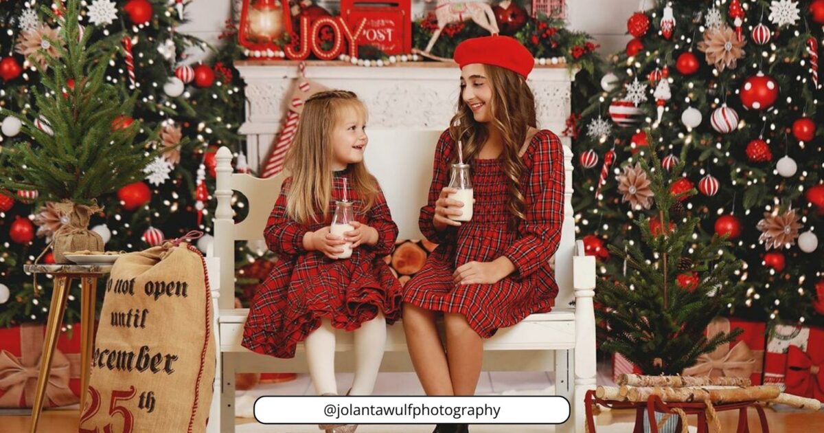 Two Girls Sitting On A Bench In Front Of Christmas Trees.