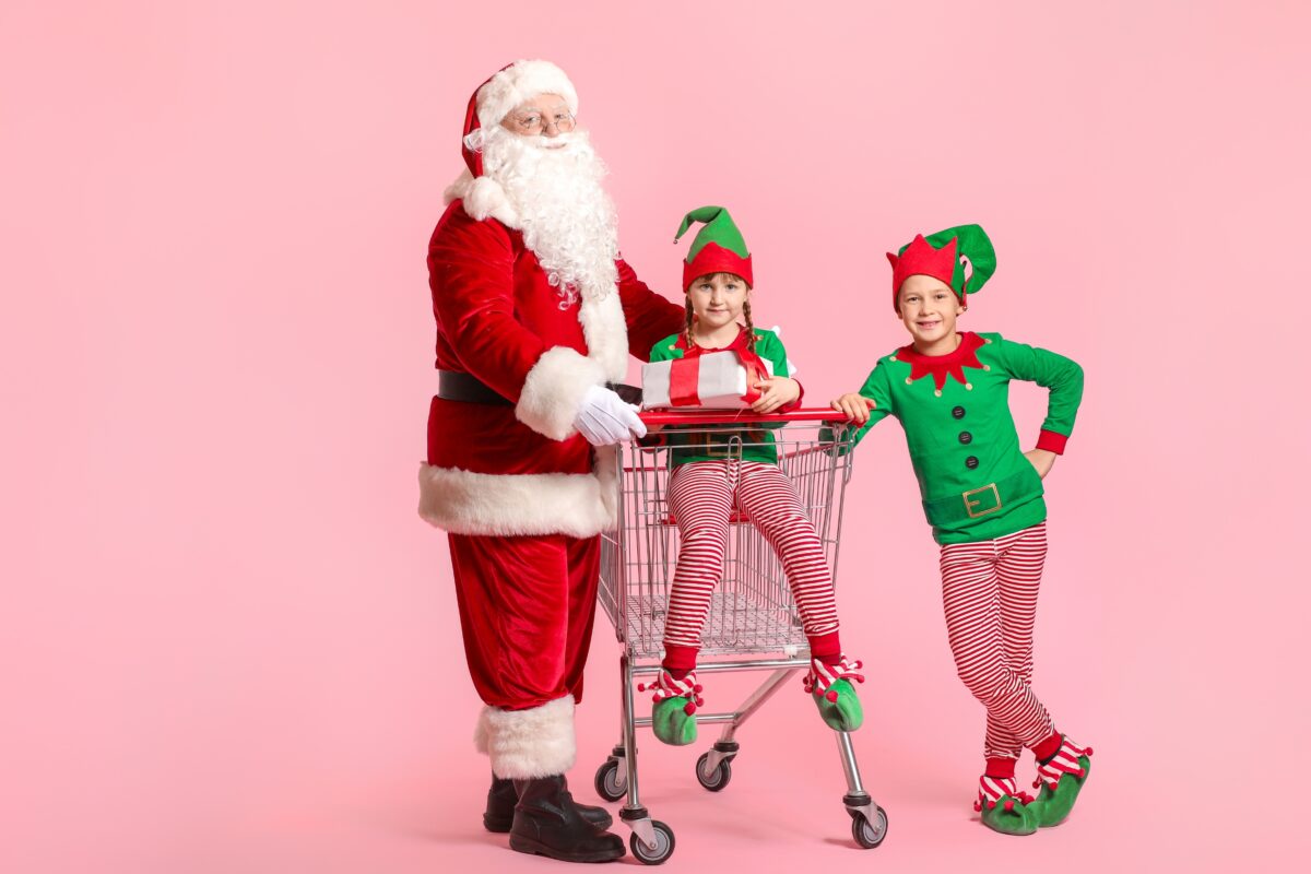 Three Children Dressed As Santa Claus Participate In Mini Sessions While Pushing A Shopping Cart.