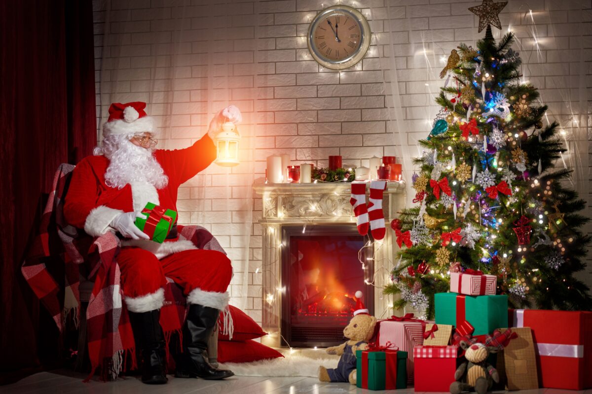 Santa Claus Sitting In Front Of A Fireplace With Presents, Available For Mini Sessions.