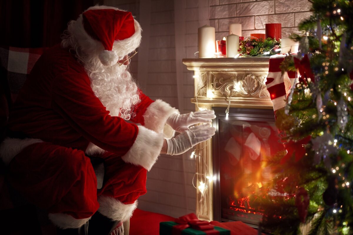 Santa Claus Sitting In Front Of A Fireplace For A Special Santa Photoshoot.