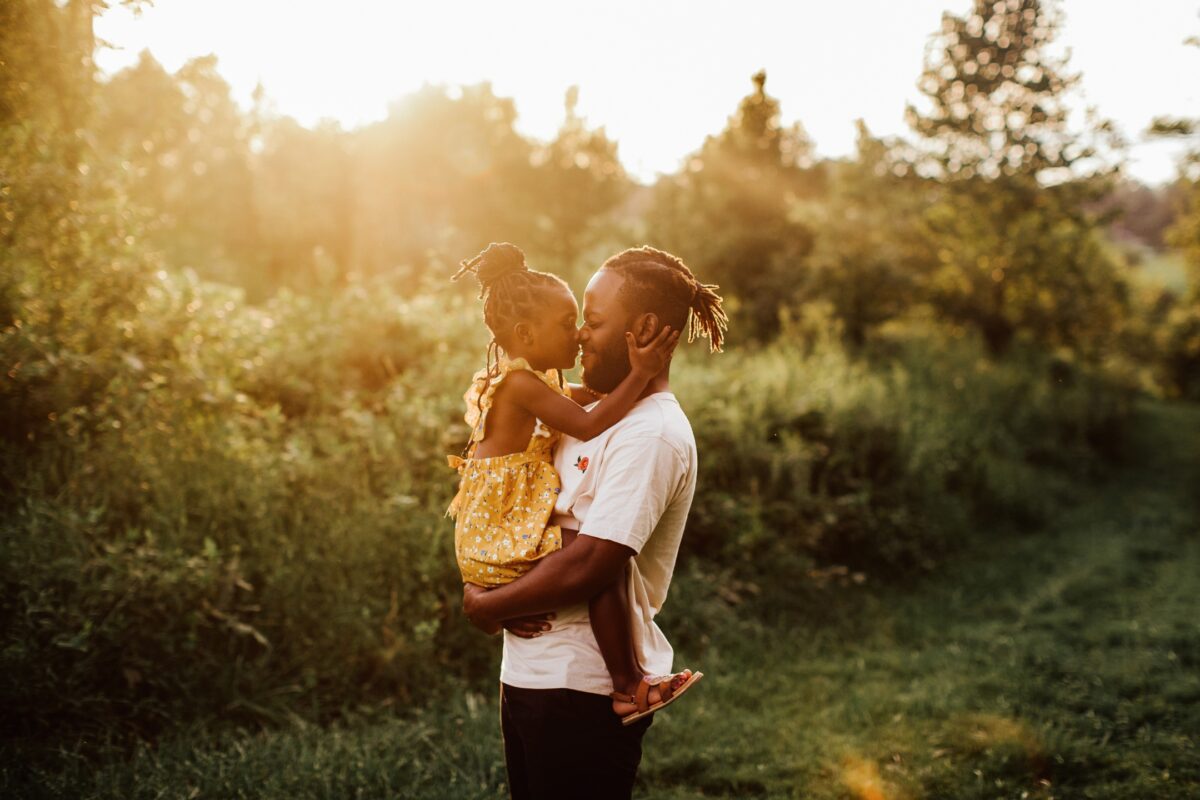 A Man And His Daughter Striking Poses In A Field At Sunset, Guided By Helpful Posing Prompts For An Engaging Photo Session.