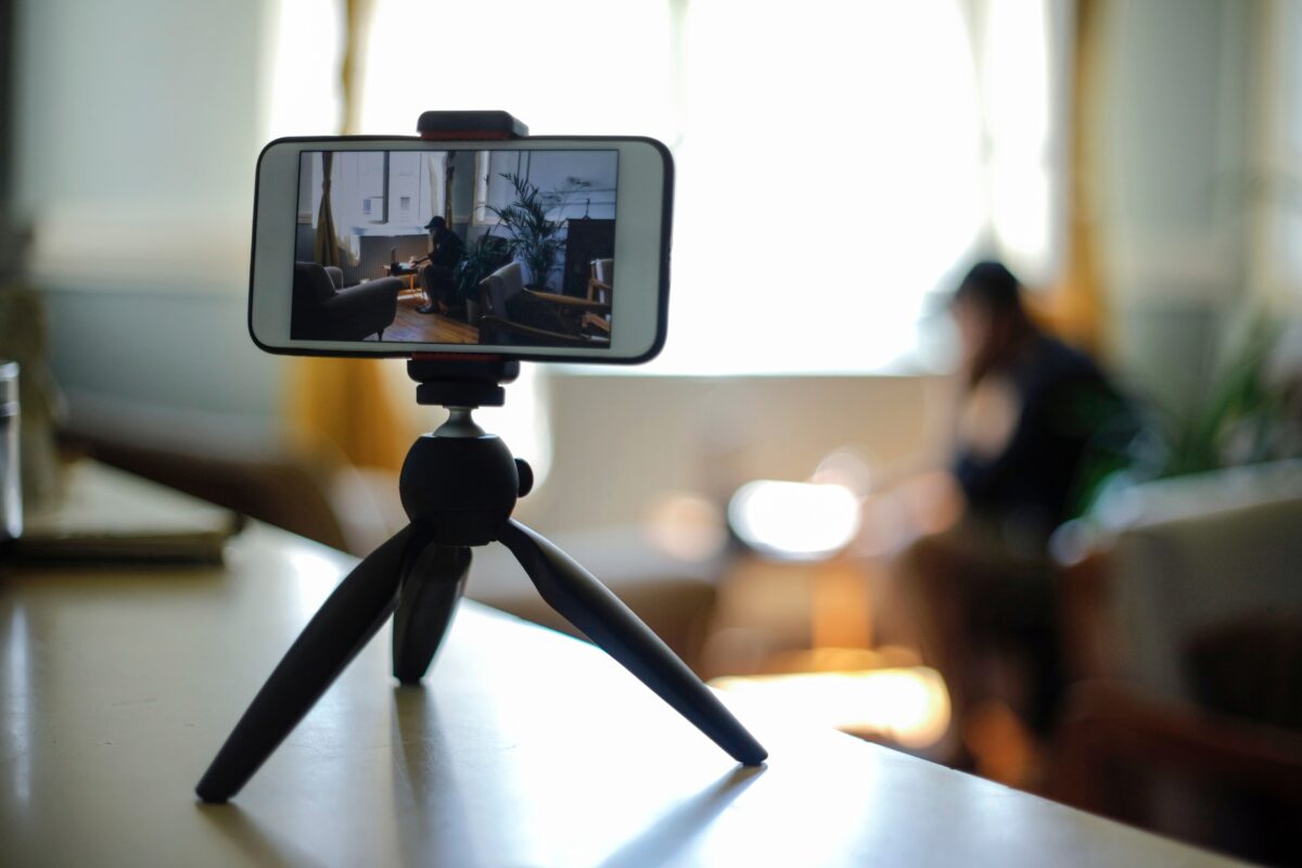 A Person Utilizing Mobile Photography Tips While Using A Cell Phone On A Tripod.