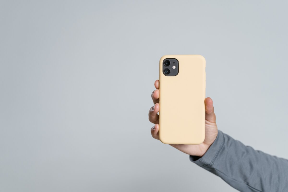 A Person Showcasing Mobile Photography Tips By Holding Up A Yellow Iphone Case Against A Sleek Gray Background.