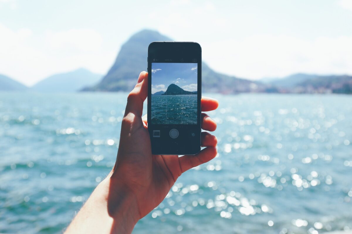 A Person Capturing The Beauty Of The Ocean With A Cell Phone Using Mobile Photography.