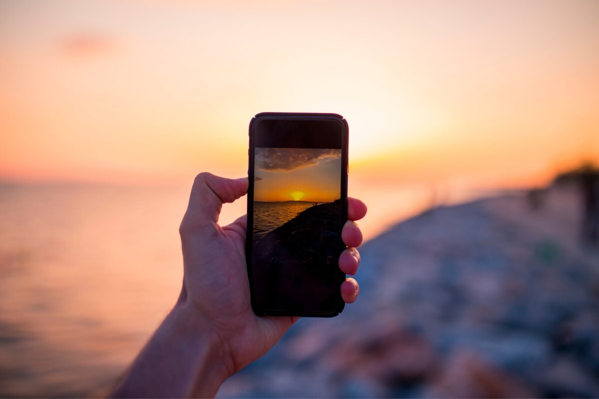 A Person Using Mobile Photography To Capture A Stunning Sunset.