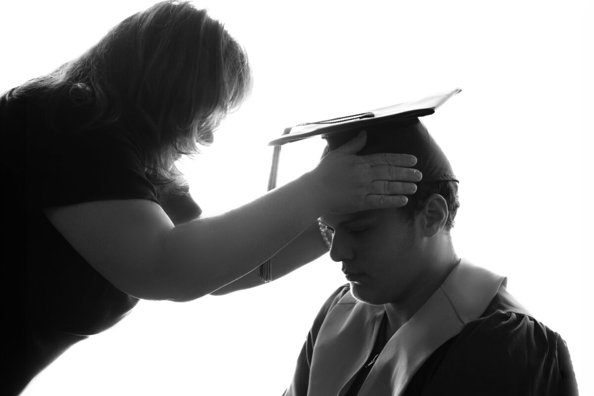 A Captivating Photograph Captures The Poignant Moment Of A Woman Tenderly Placing A Graduation Cap On A Man, Highlighting The Significance Of Photography In Preserving Important Milestones.