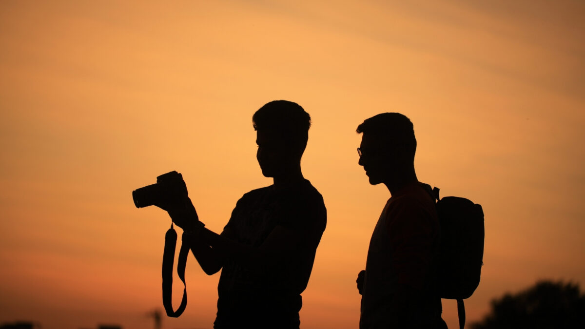 Silhouette Of Two Men Capturing Stunning Sunset Photos.