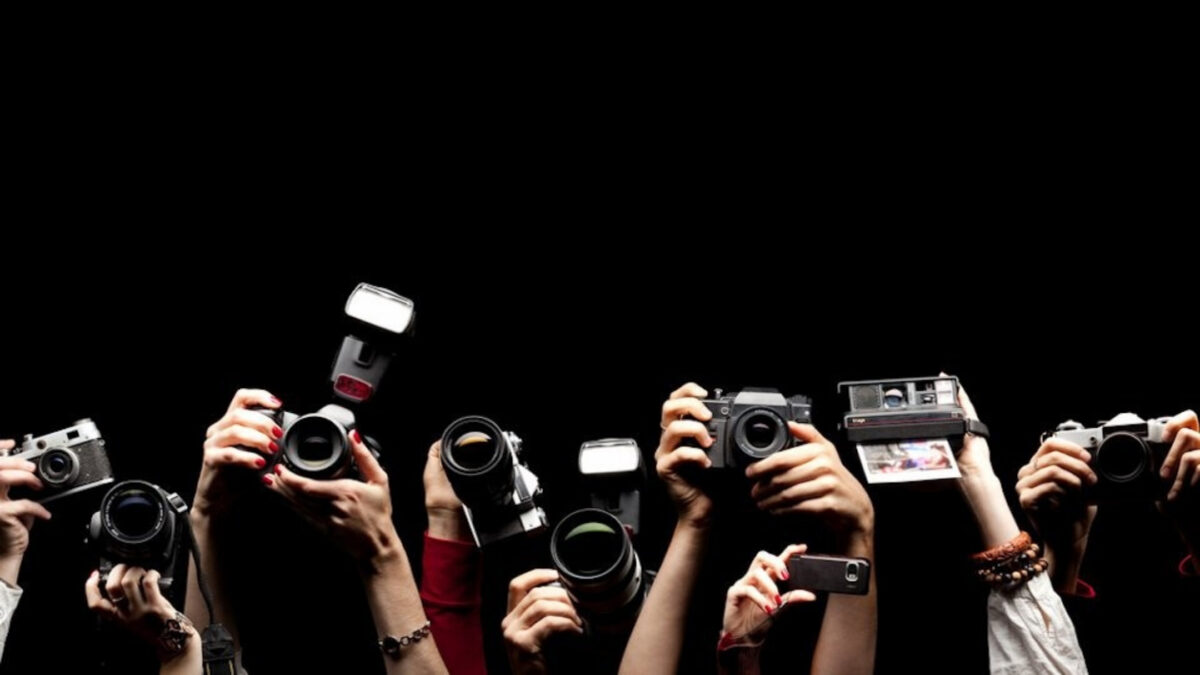 Join A Group Of Photographers In Front Of A Black Background, Capturing Memorable Shots With Their Cameras.