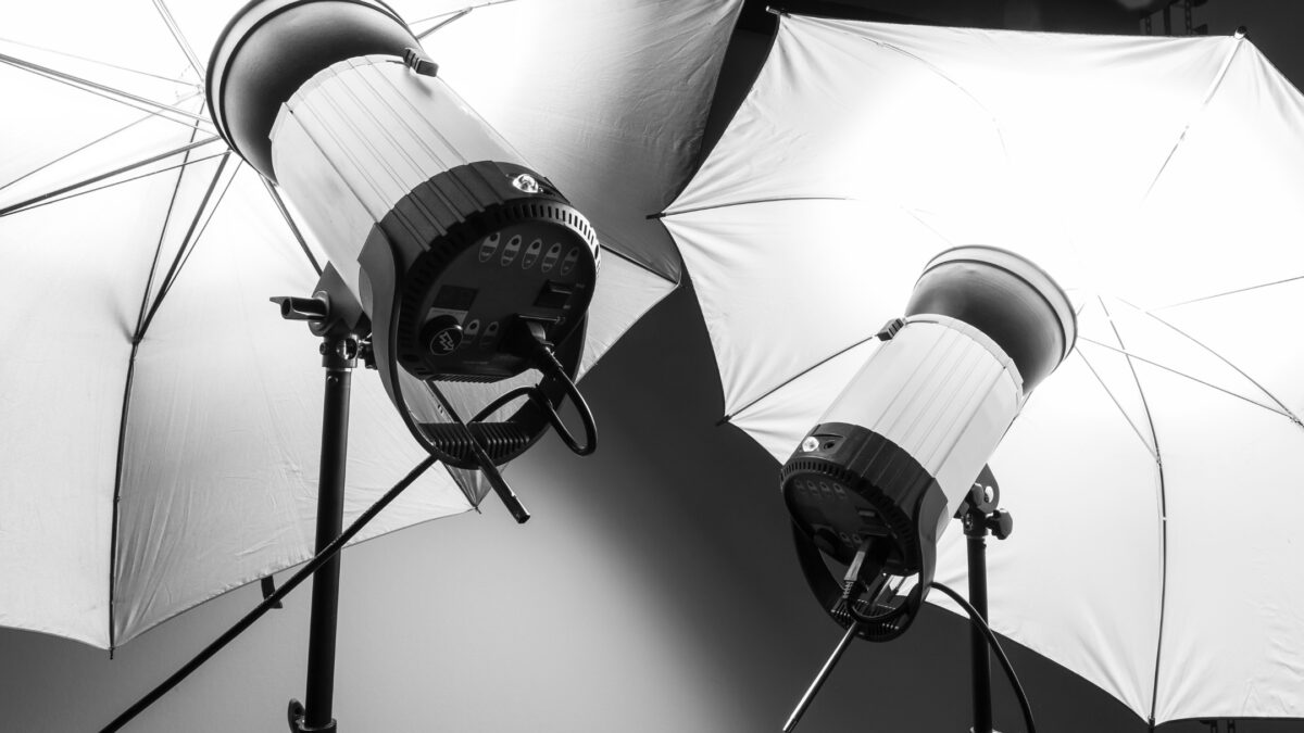 A Black And White Photo Of Two Umbrellas In A Studio, Captured Using Professional Photography Lighting Kit.