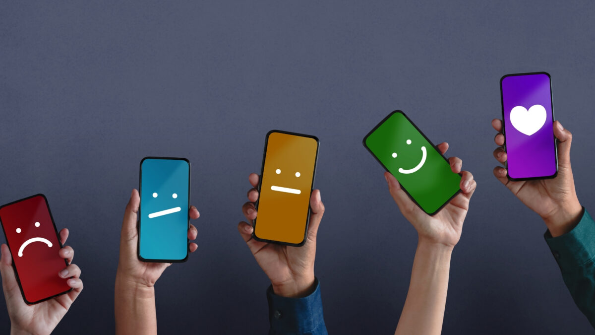 A Group Of People Holding Smartphones With Different Colored Smiley Faces On Them, Providing Feedback On Photos.