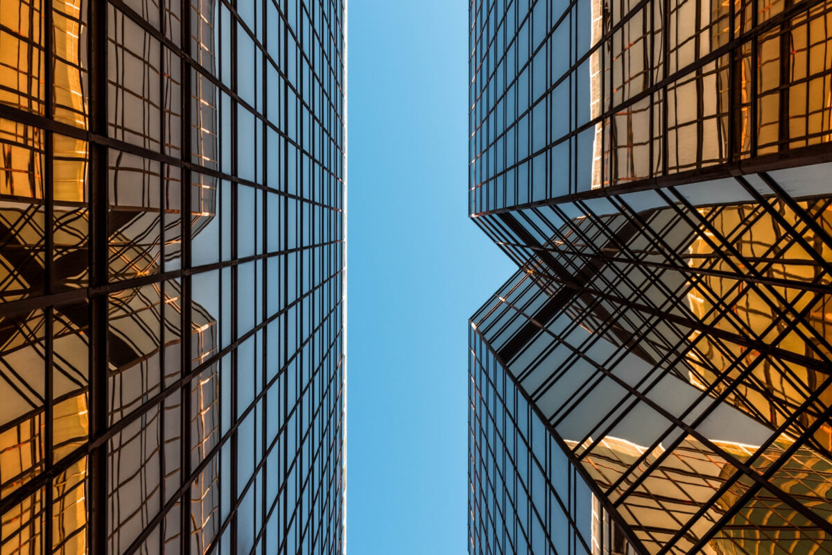 A Composition Of Two Tall Buildings Against A Blue Sky Backdrop.