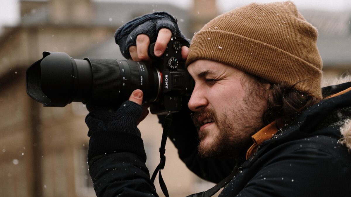 A Man Making Mistakes As A Photographer While Holding A Camera In The Snow.