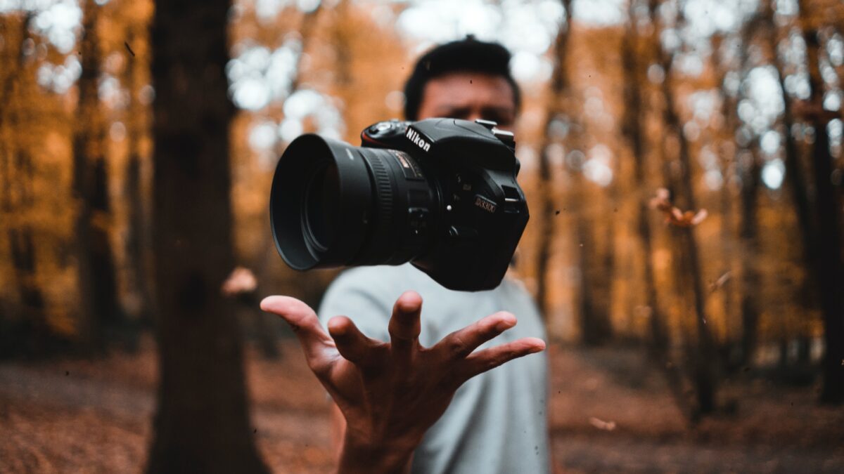 A Man, Plagued By Mistakes As A Photographer, Holding A Camera In The Woods.