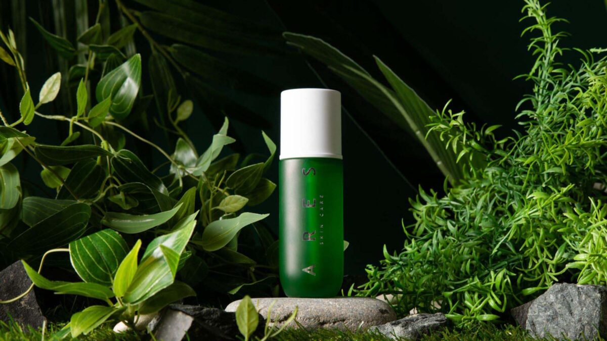 A Green Bottle Nestled Among Lush Plants And Rocky Backdrop, Perfect For Photography Ideas.