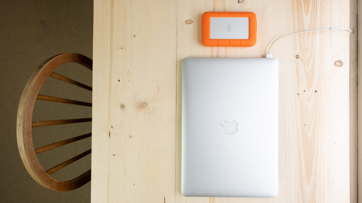 An Apple Macbook Pro Helps Organize Digital Photos On A Wooden Table.