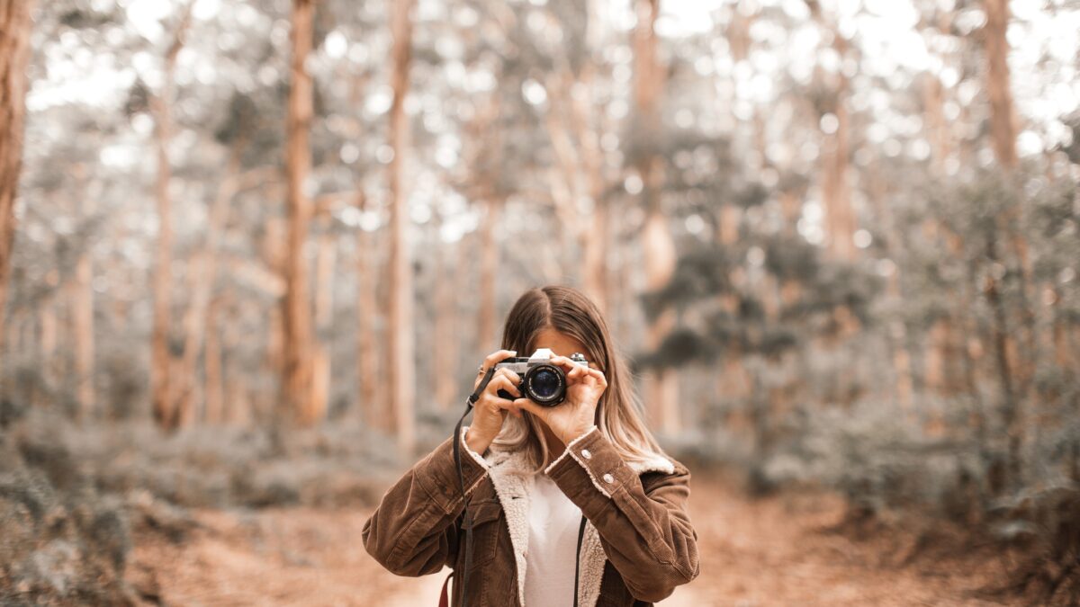 A Woman, Making Mistakes As A Photographer, Captures A Picture With Her Camera In The Woods.