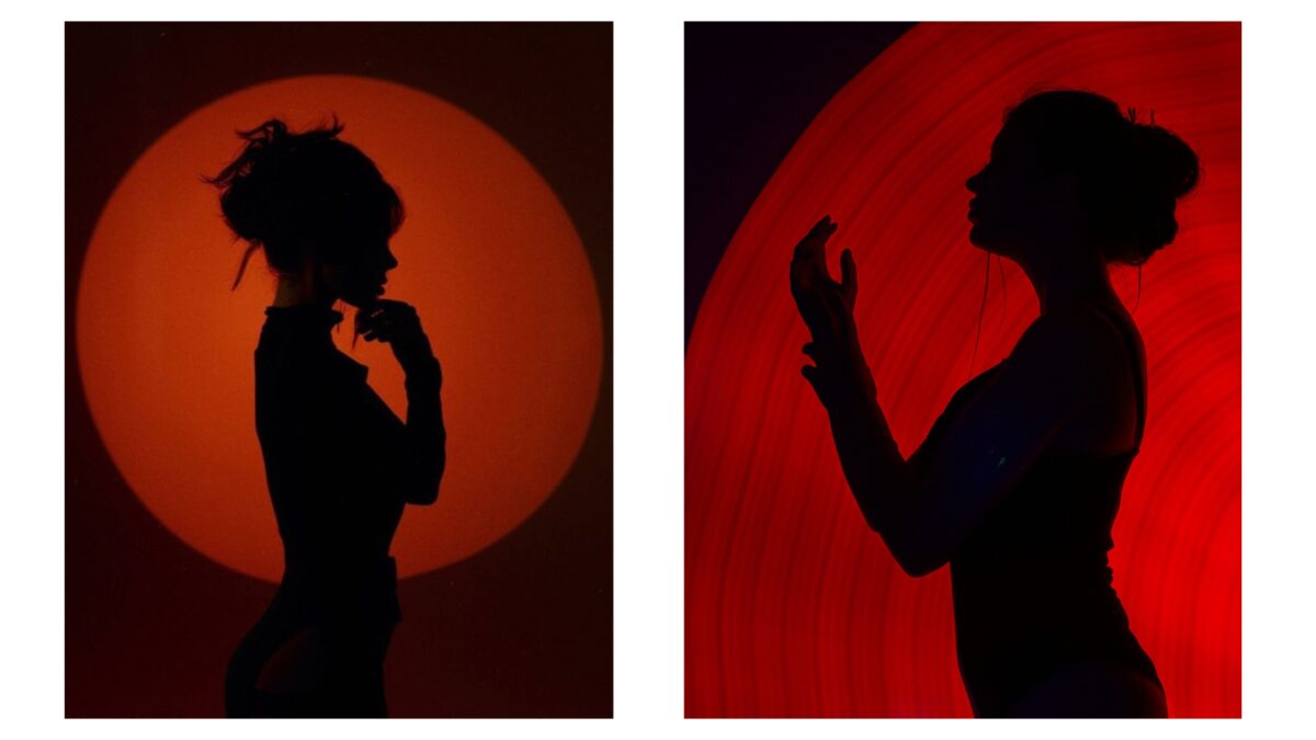 Two Shadowy Silhouettes Of A Woman Standing In Front Of A Captivating Red Light.