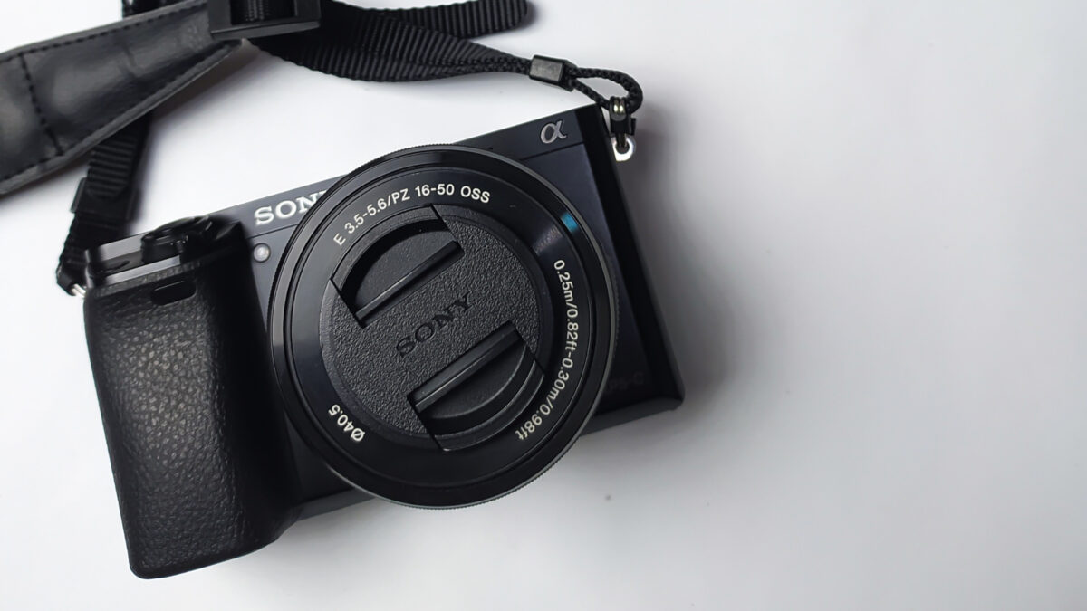 A Black Camera With A Strap Attached To It, Available In Both Dslr And Mirrorless Options.