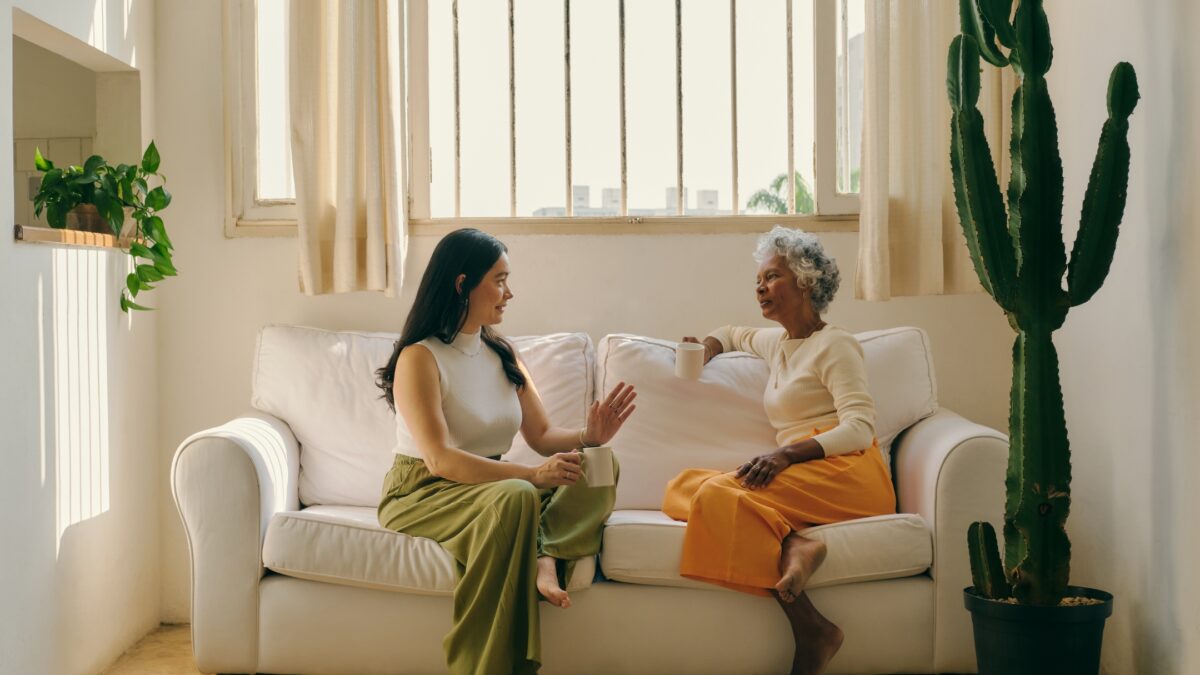 Two Elderly Women Sitting On A Couch In A Perfect Indoor Living Room.