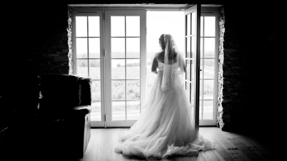 A Bride Is Posing For Perfect Indoor Photos In Front Of An Open Door.