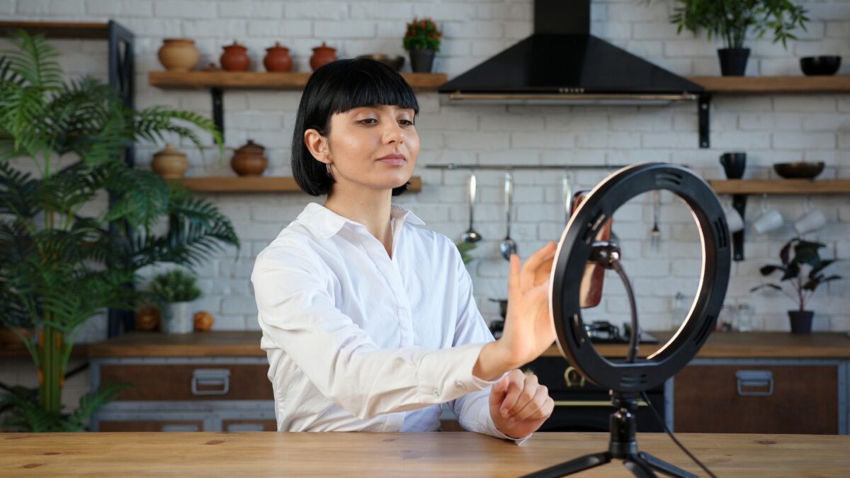 A Woman Is Holding A Photography Ring Light In Front Of A Table.